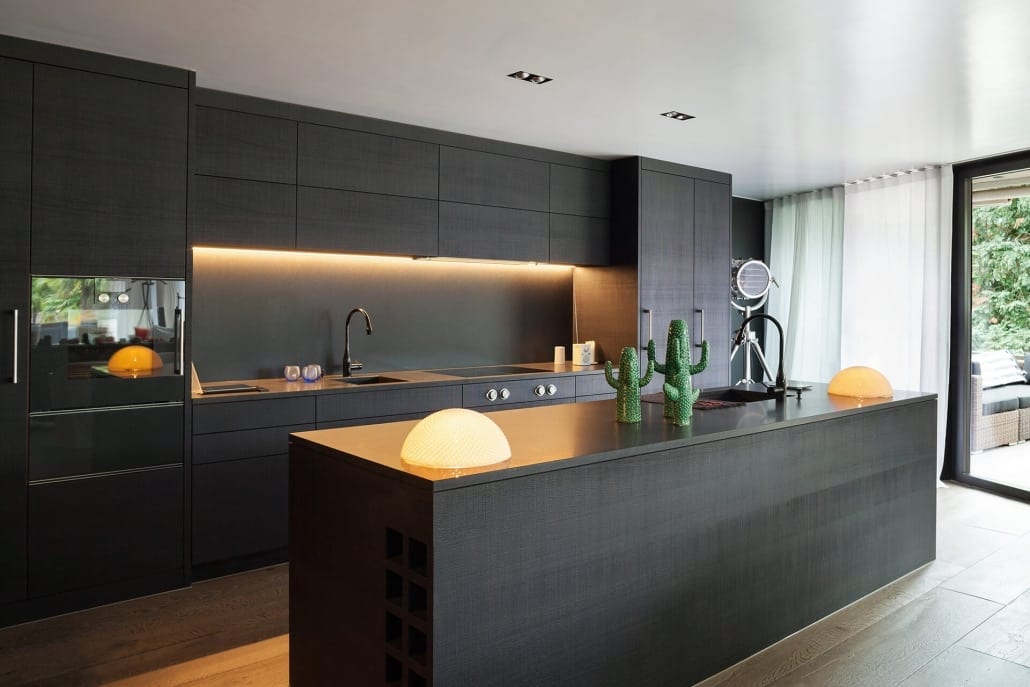 A wide, eye-level shot of a sleek, contemporary kitchen featuring dark wood cabinetry