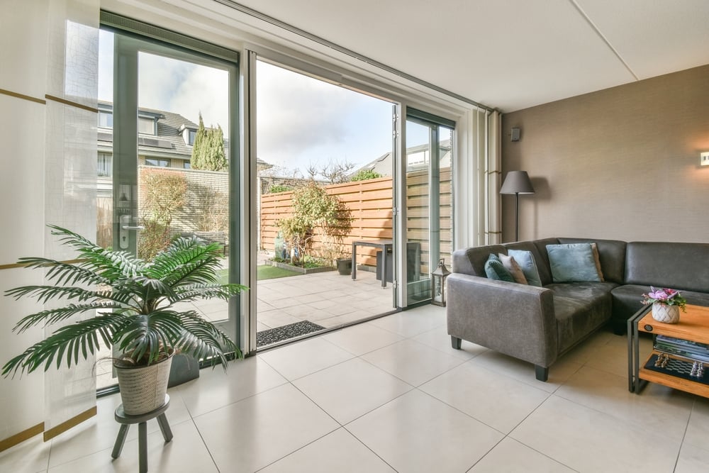 A wide shot of a modern living room featuring a large grey sectional sofa and tile flooring