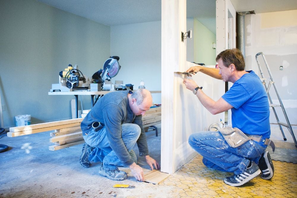 Two construction workers in blue shirts and jeans working on interior renovations