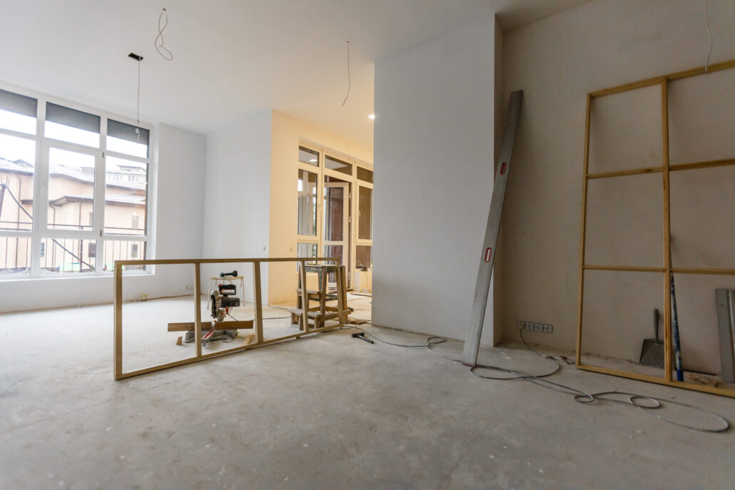 Interior home renovation in progress with timber wall framing and concrete floors showing structural works