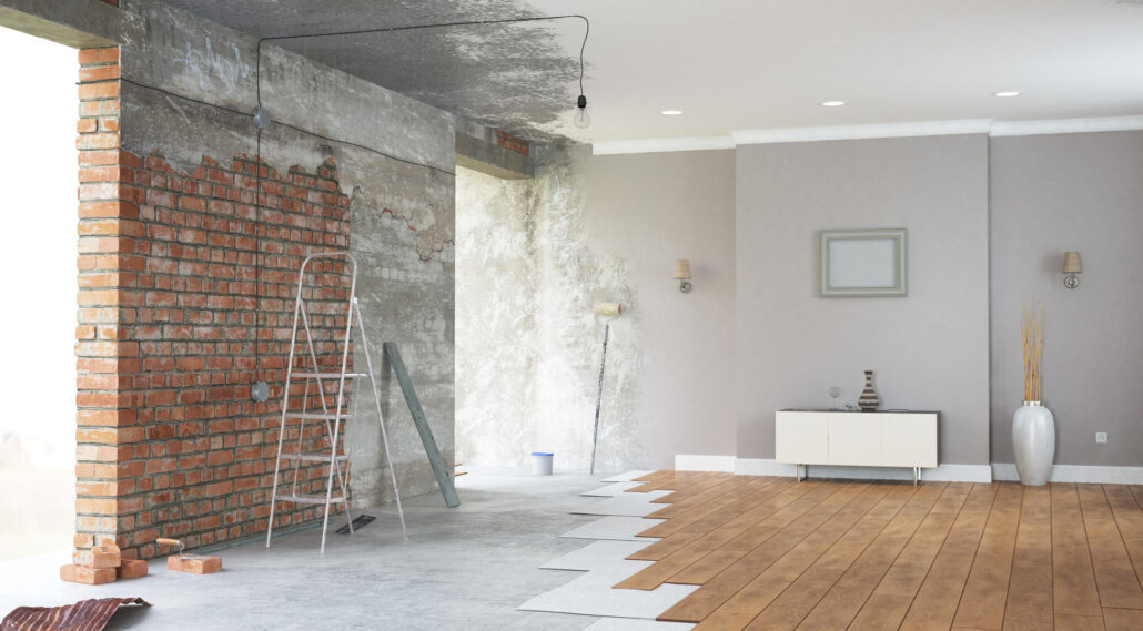 Open plan living room mid-renovation with exposed brick wall and ladder beside a nearly finished timber floor and painted interior in Lake Macquarie