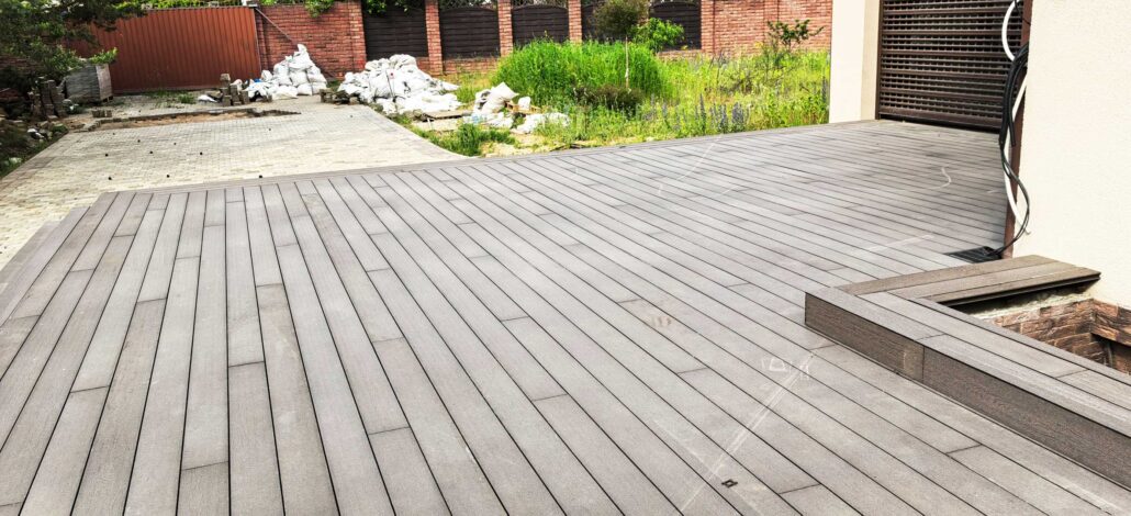 A freshly installed wooden deck is shown in a backyard setting