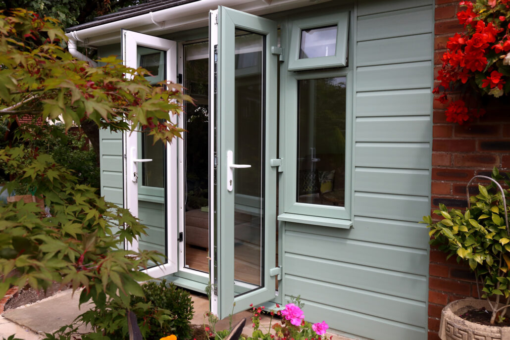 External view of a newly built granny flat with sage green cladding and French doors opening to garden in Beresfield NSW
