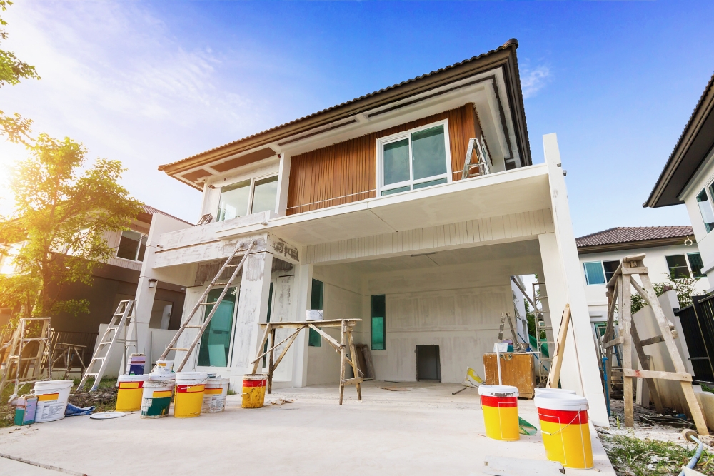 A low-angle shot of a modern two-storey house undergoing painting and exterior renovation