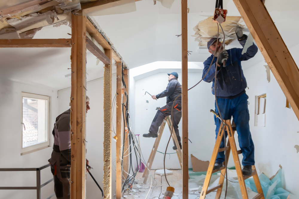 Construction workers working on electrical wiring and interior framing during a home renovation.