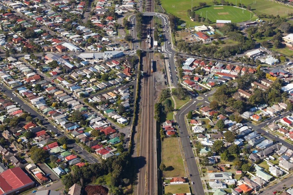 Aerial view of a residential suburban neighborhood split by railway tracks and surrounding roads.