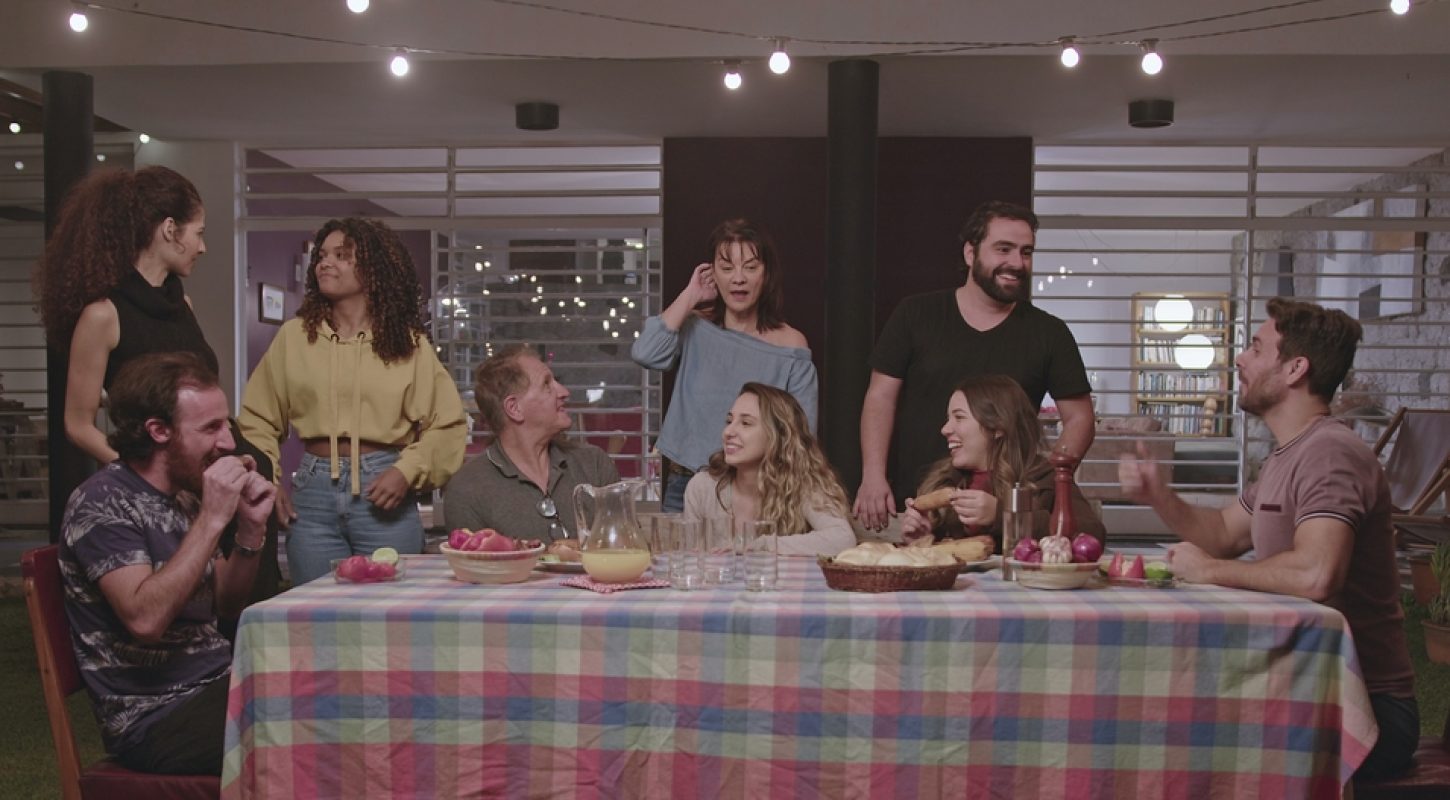 A group of diverse friends and family members of various ages laughing and talking around a large dinner table